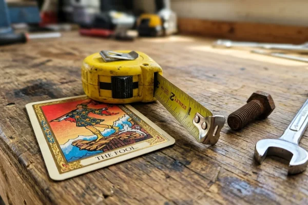 A rugged man checking his smartphone for astrology updates while leaning on a workbench.