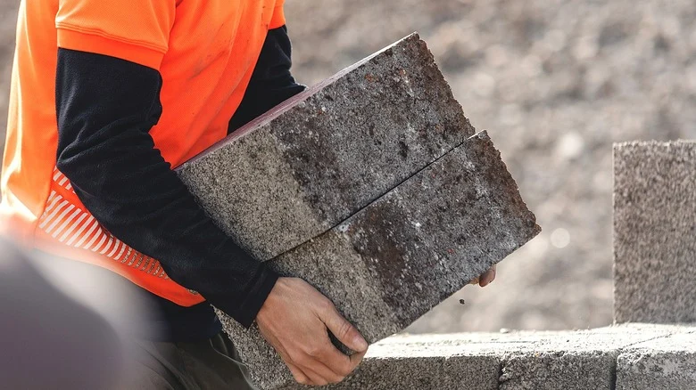 Construction worker carrying two concrete blocks
