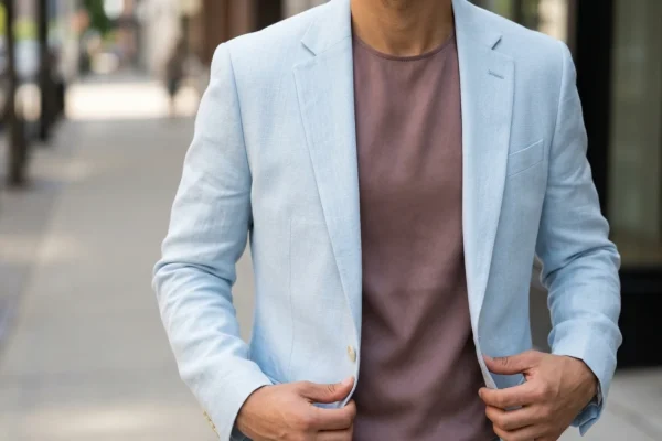 Charlize Theron walking a 2026 red carpet in a tailored pale blue suit with a mauve silk blouse.