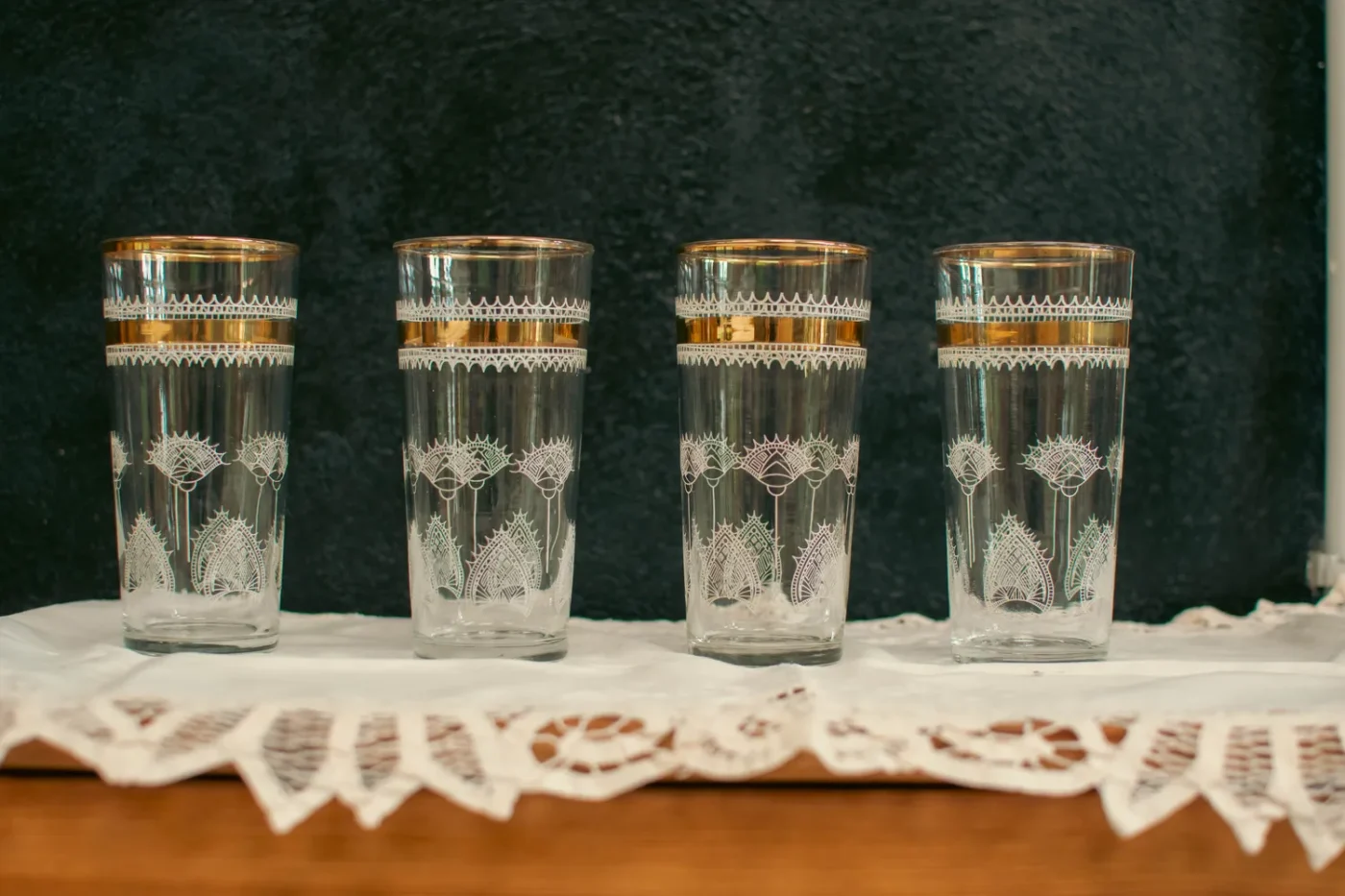 Four decorative glasses arranged in a row on a lacecovered surface