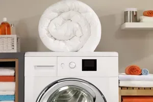 heavy comforter sitting on washing machine for laundry