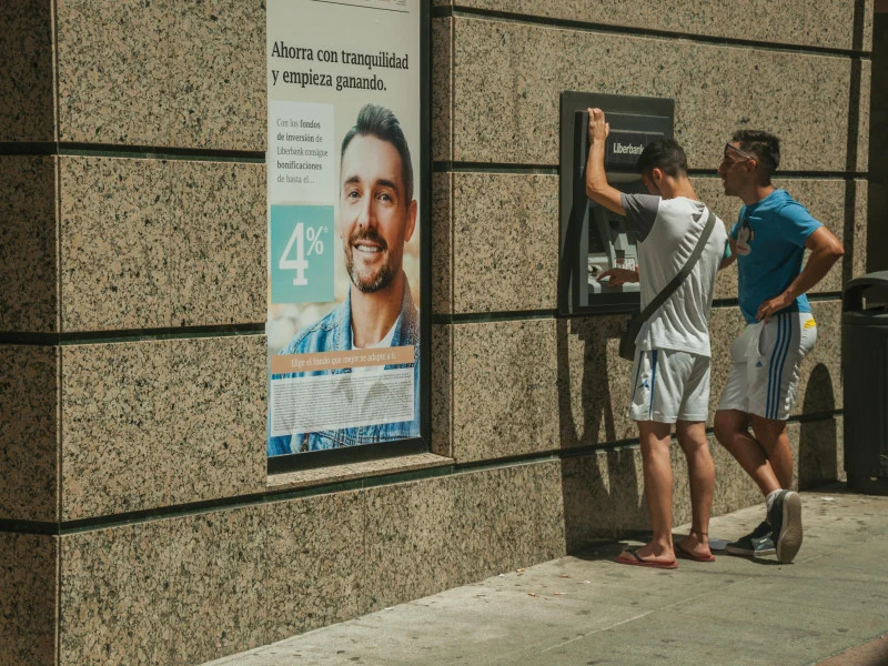 Jóvenes usando un cajero automático en la calle en un dÃa soleado en Mérida