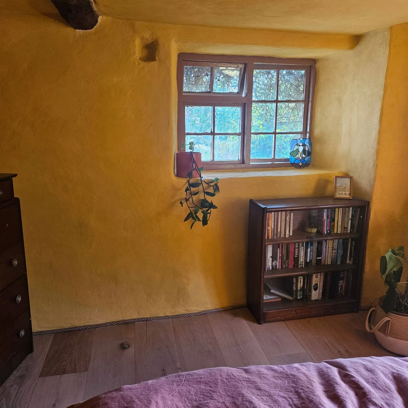 yellow bedroom with brown windows and wooden flooring