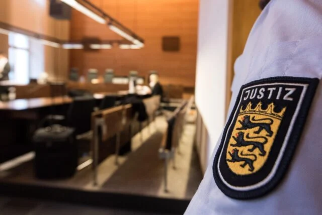 Ein Justizbeamter steht am einem Prozessbeginn im Sitzungssaal des Gerichts.