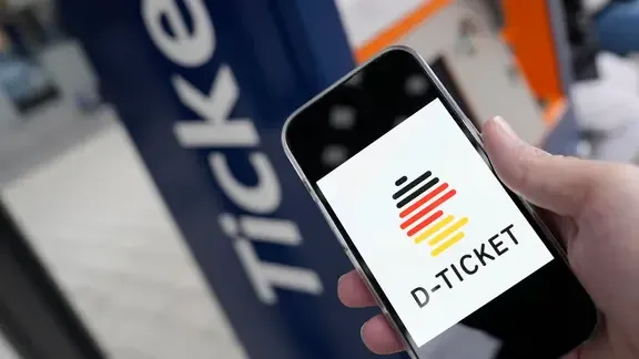 Eine Person hält ein Smartphone, auf dem ein Deutschlandticket geöffnet ist, in der Hand.