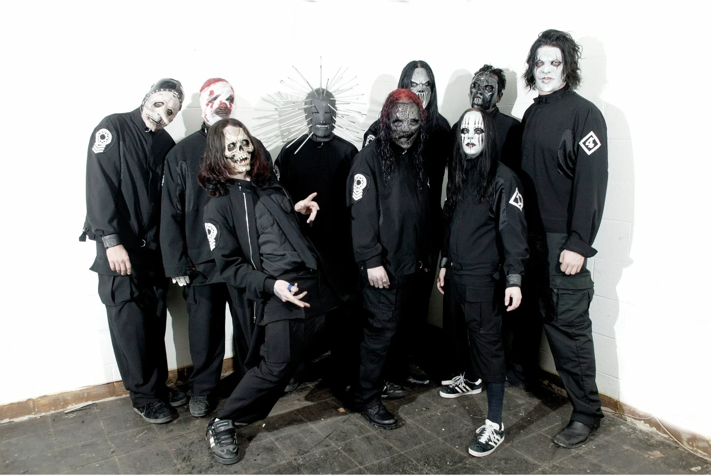 Nine members of Slipknot posing for a group photo in their stage costumes.