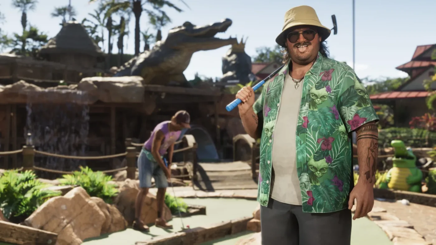Rockstar Games Cal Hampton, a character from GTA 6, stands in front of an alligator-themed crazy golf course. He holds a putter over one shoulder, and pulls a tongue-out face at the viewer. His loud, green, floral shirt stands out against the browns of the golf course. Behind him, a companion can be seen lining up an attempted putt, while a large alligator statue looms over the course.