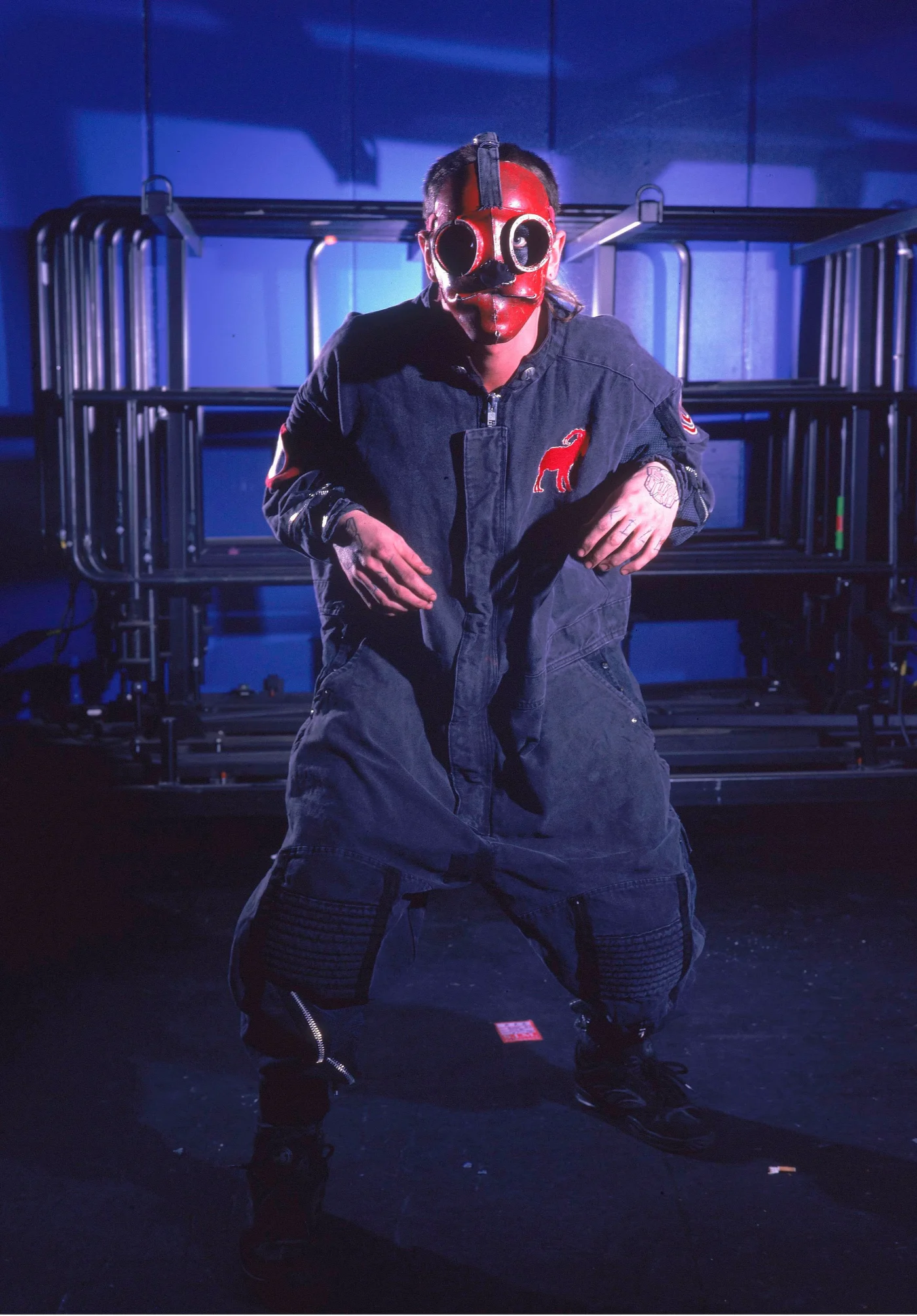 Sid Wilson of Slipknot wearing a red and black mask and dark jumpsuit.