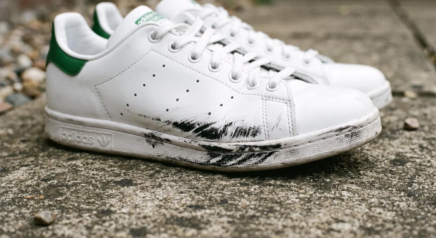 WeiĂźe Turnschuhe mit schwarzen Schrammen